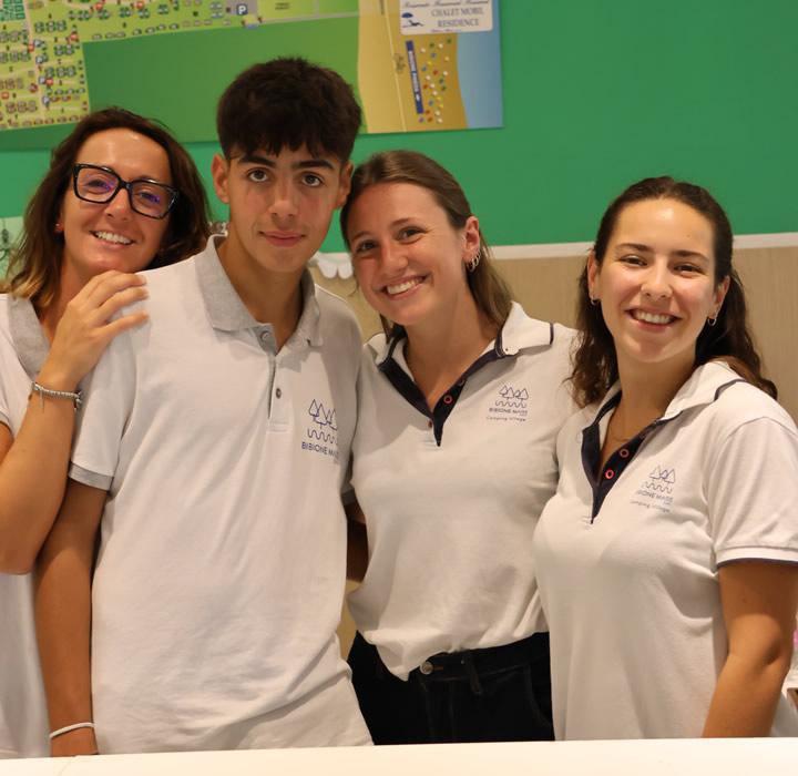 Four smiling young people in white uniforms, radiating joy and friendship.
