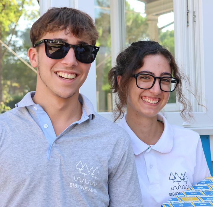 Two smiling young people in glasses and polos, radiating joy and friendship.